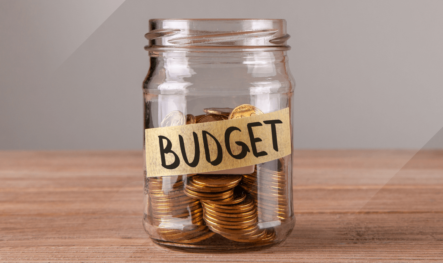 Image of coins in a jar with Budget written on tape across the front representing SEO vs. PPC